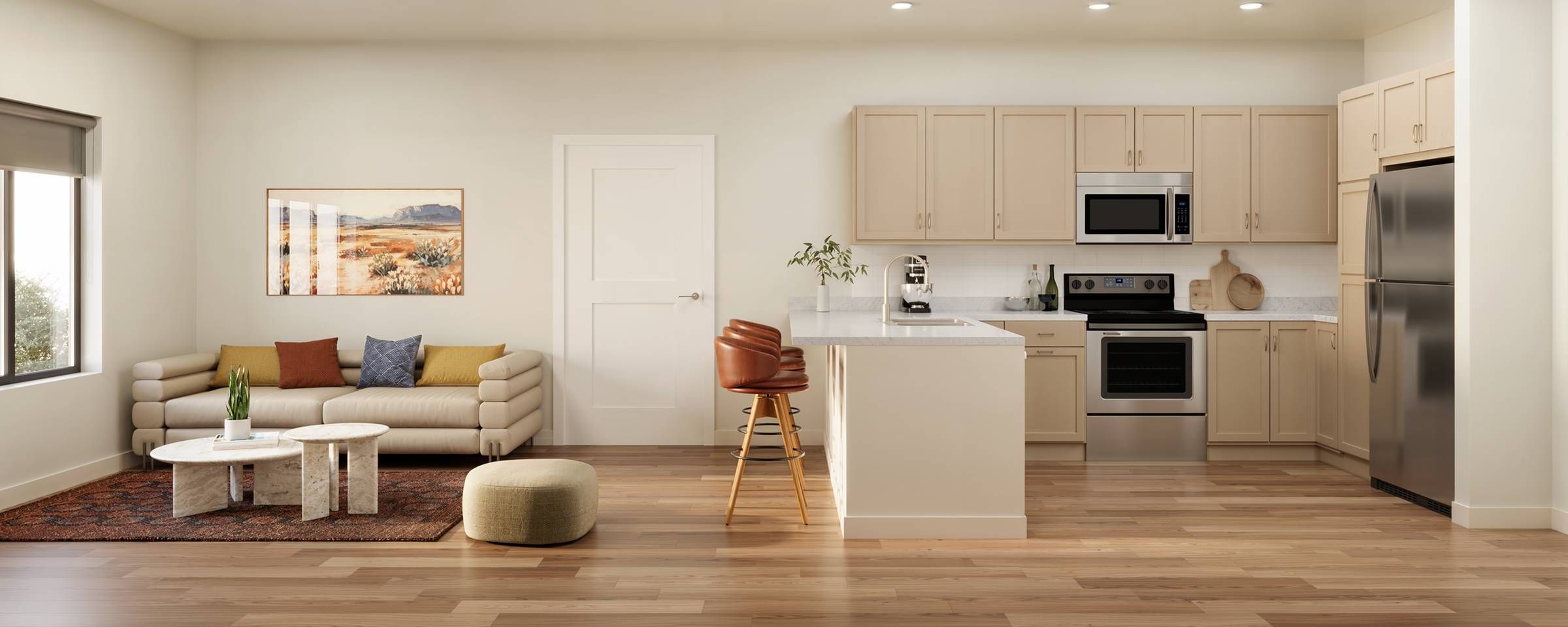 Emberwood apartments Modern beige kitchen with stainless steel appliances, island seating, and a cozy living area with a sofa.