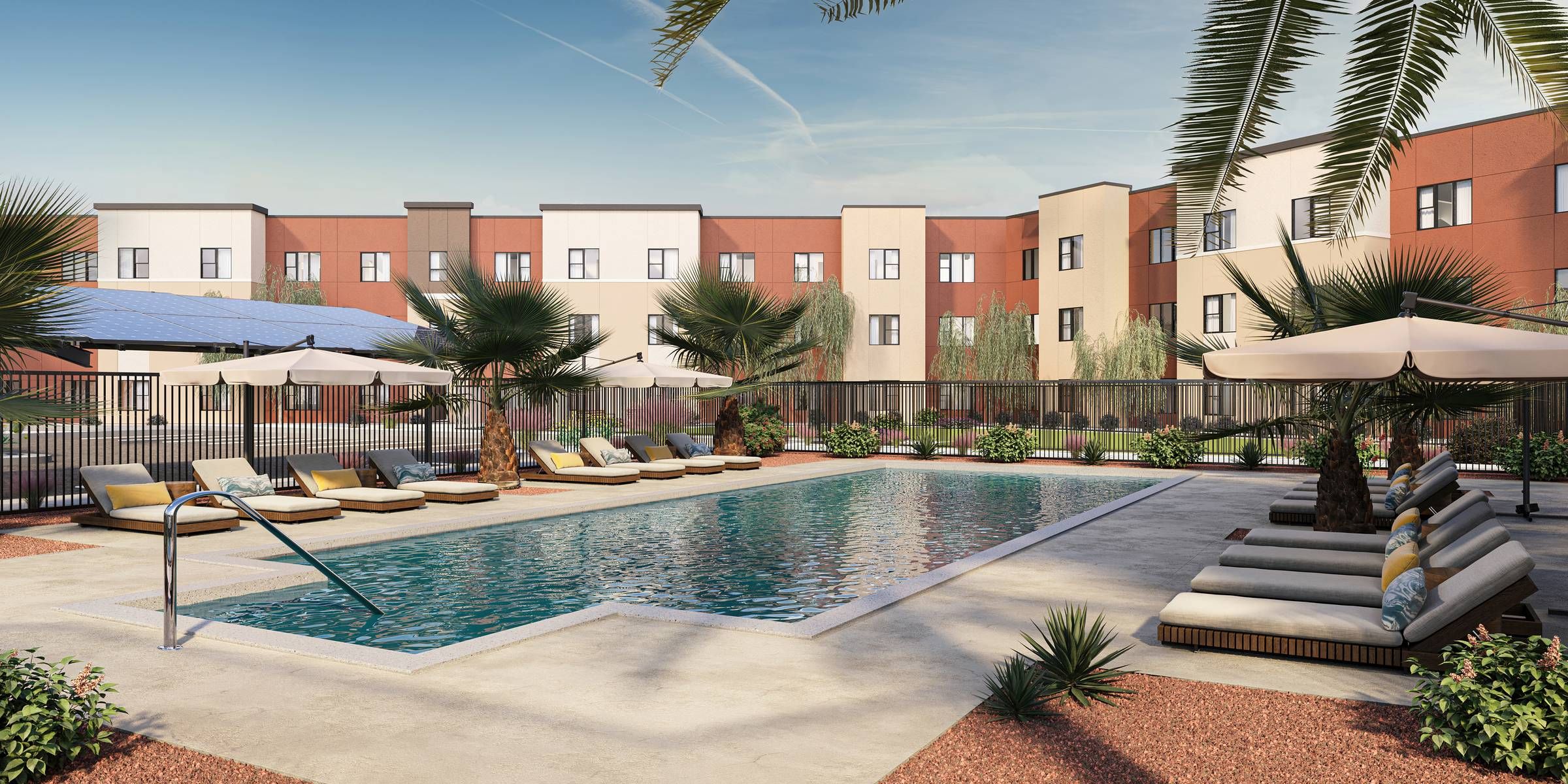 Emberwood apartments Rectangular outdoor pool with lounge chairs, umbrellas, palm trees, and a modern apartment building in the background.
