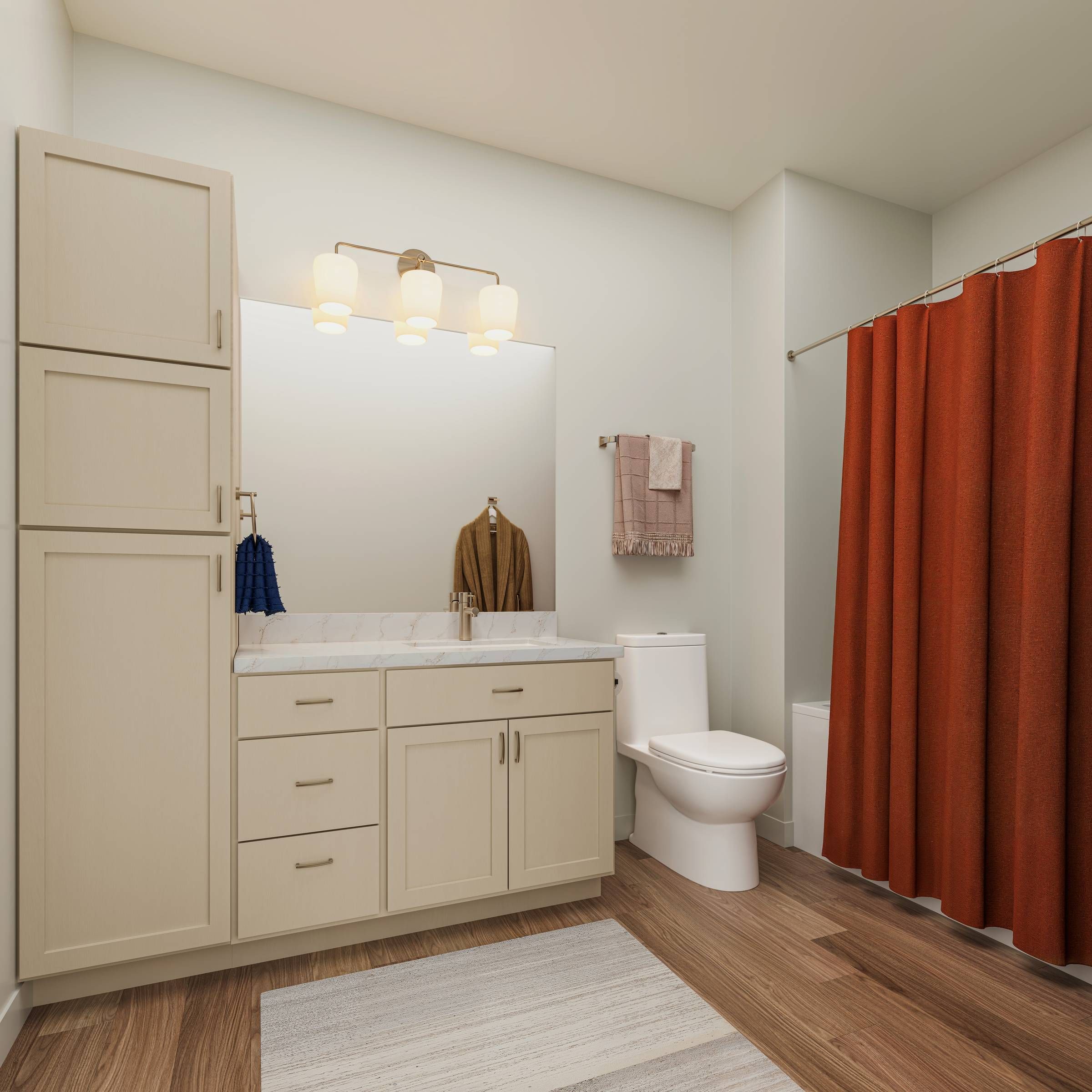 Emberwood apartments Modern bathroom with beige cabinets, a large mirror, white toilet, and red shower curtain on the right.